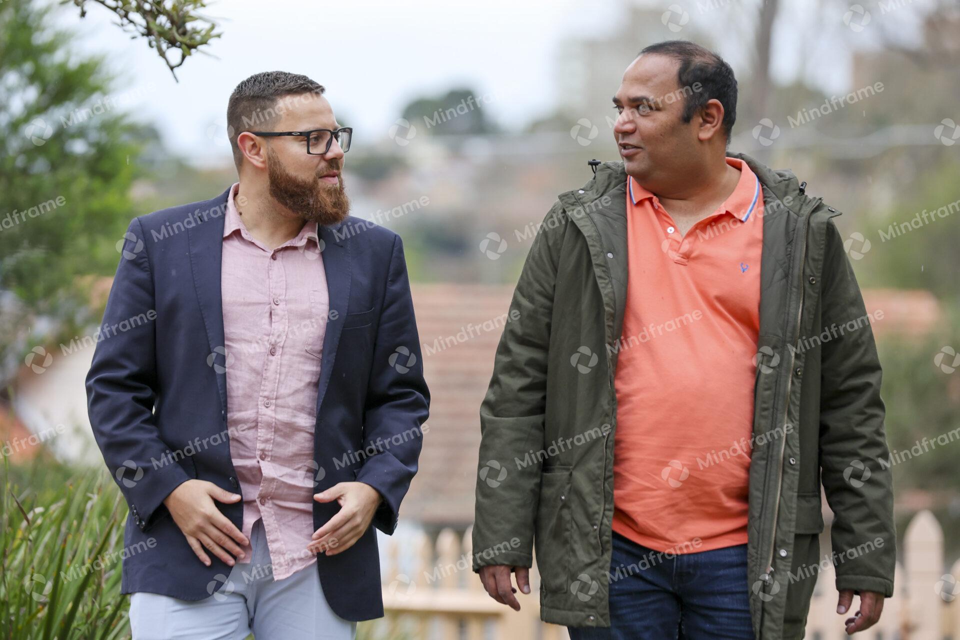 Two people talking and walking outside in front of a house