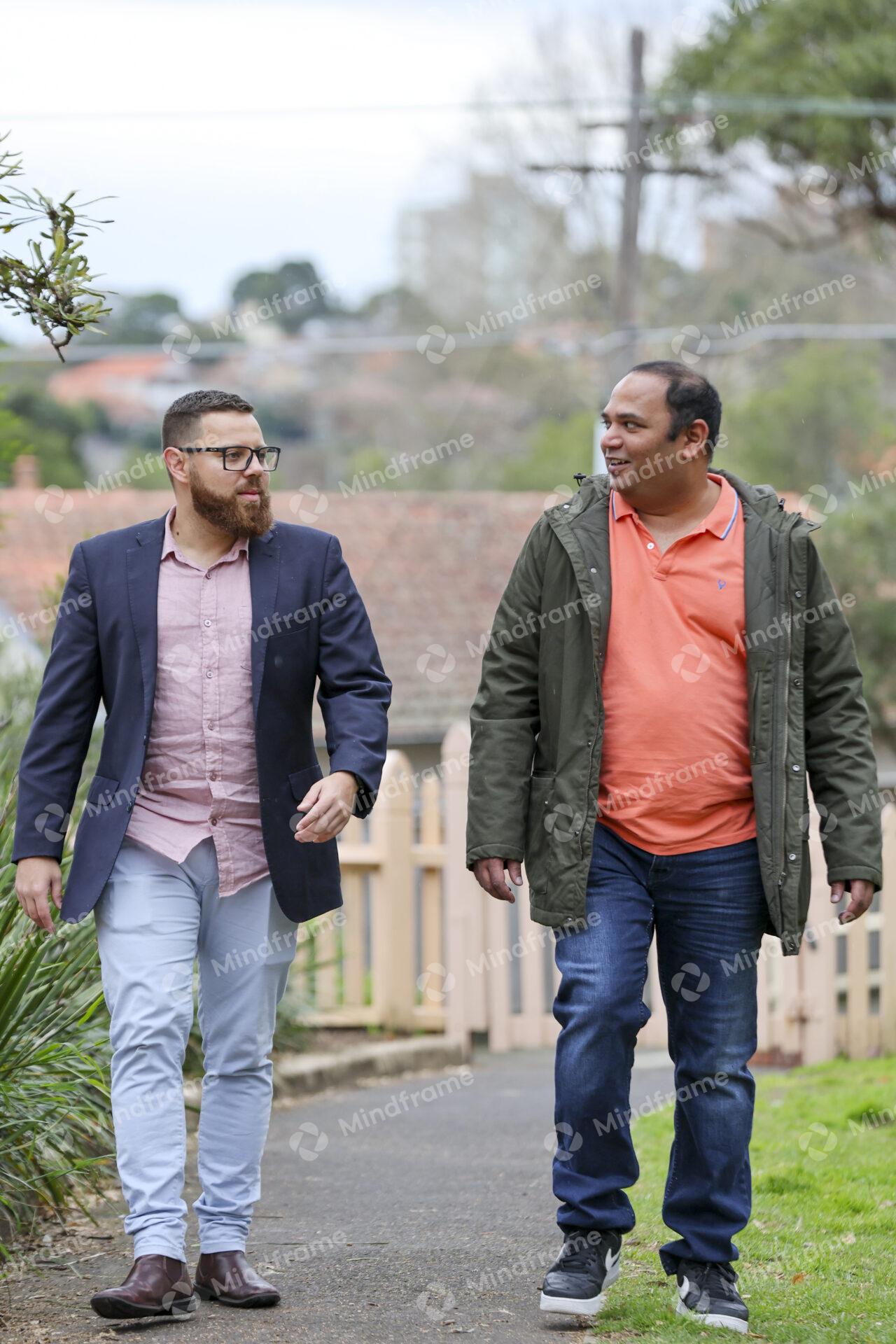 Two people talking and walking outside in front of a house