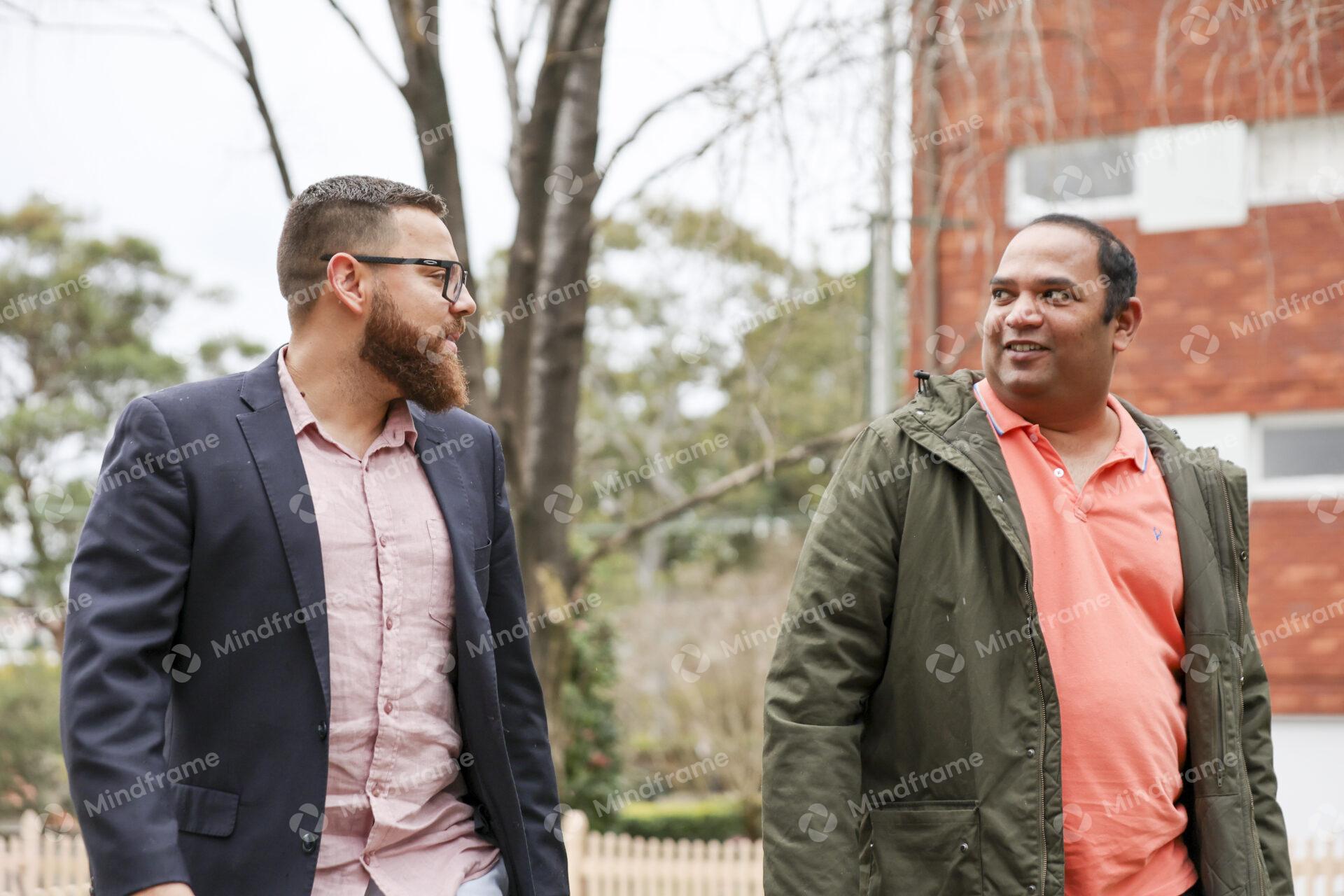 Two people talking and walking outside in front of units