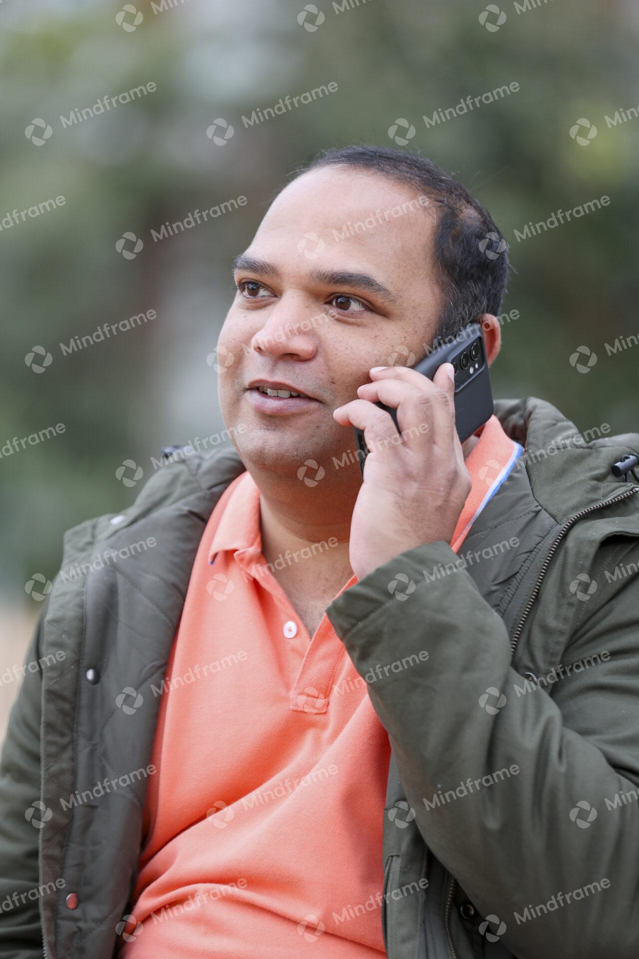 One person sitting talking on the phone in front of trees