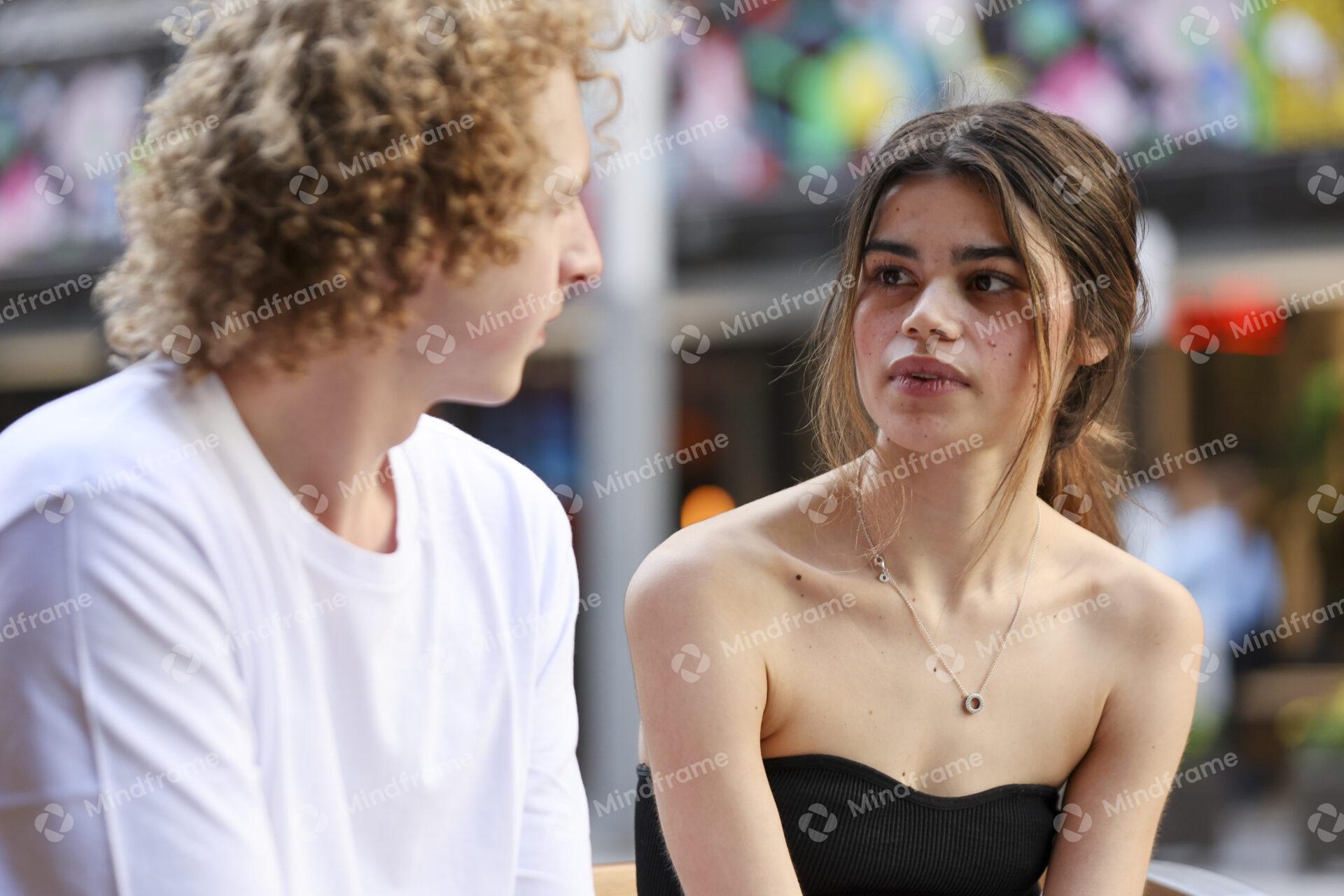 Two people talking while seated on a bench in an urban landscape