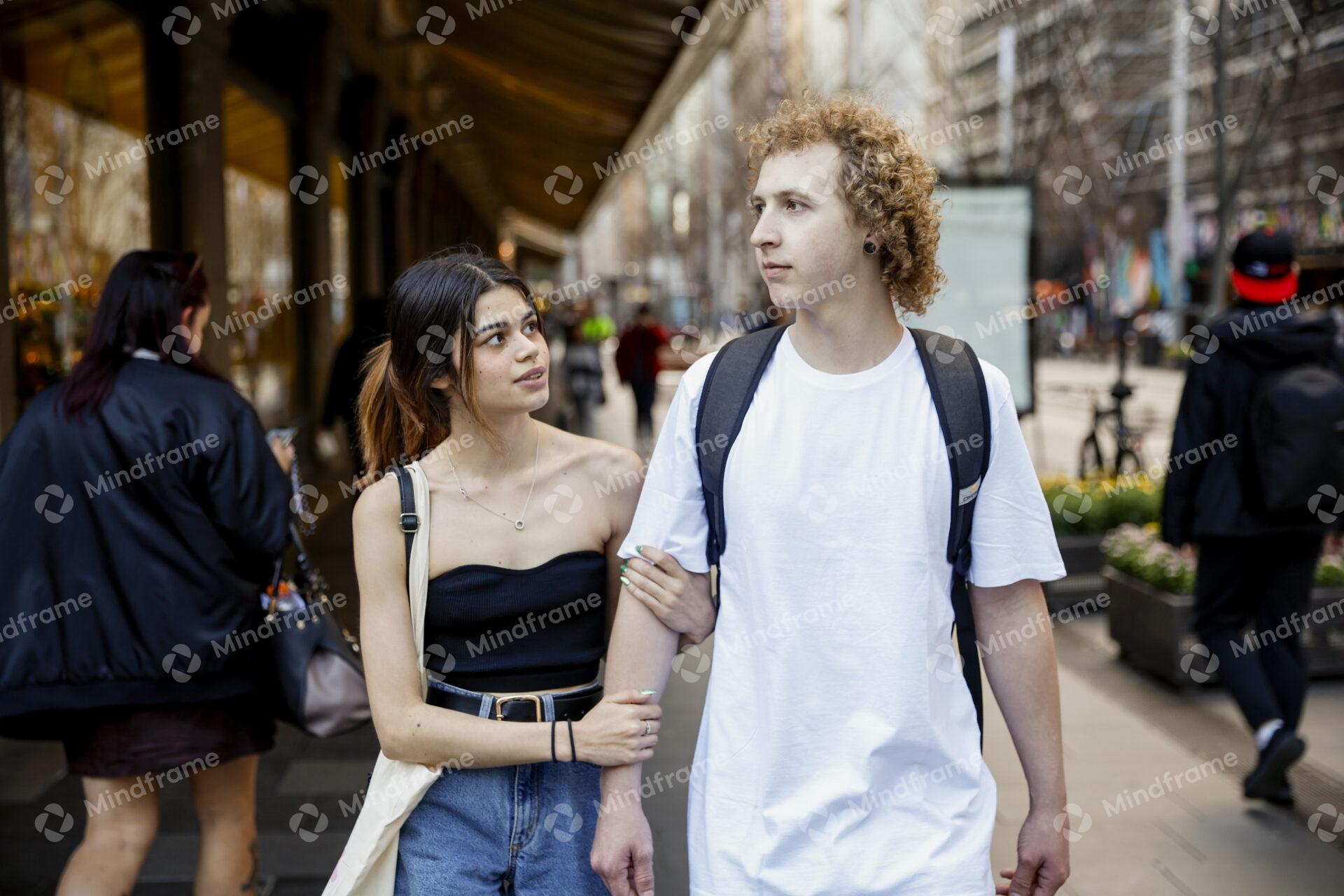 Two people linking arms walking along a city street