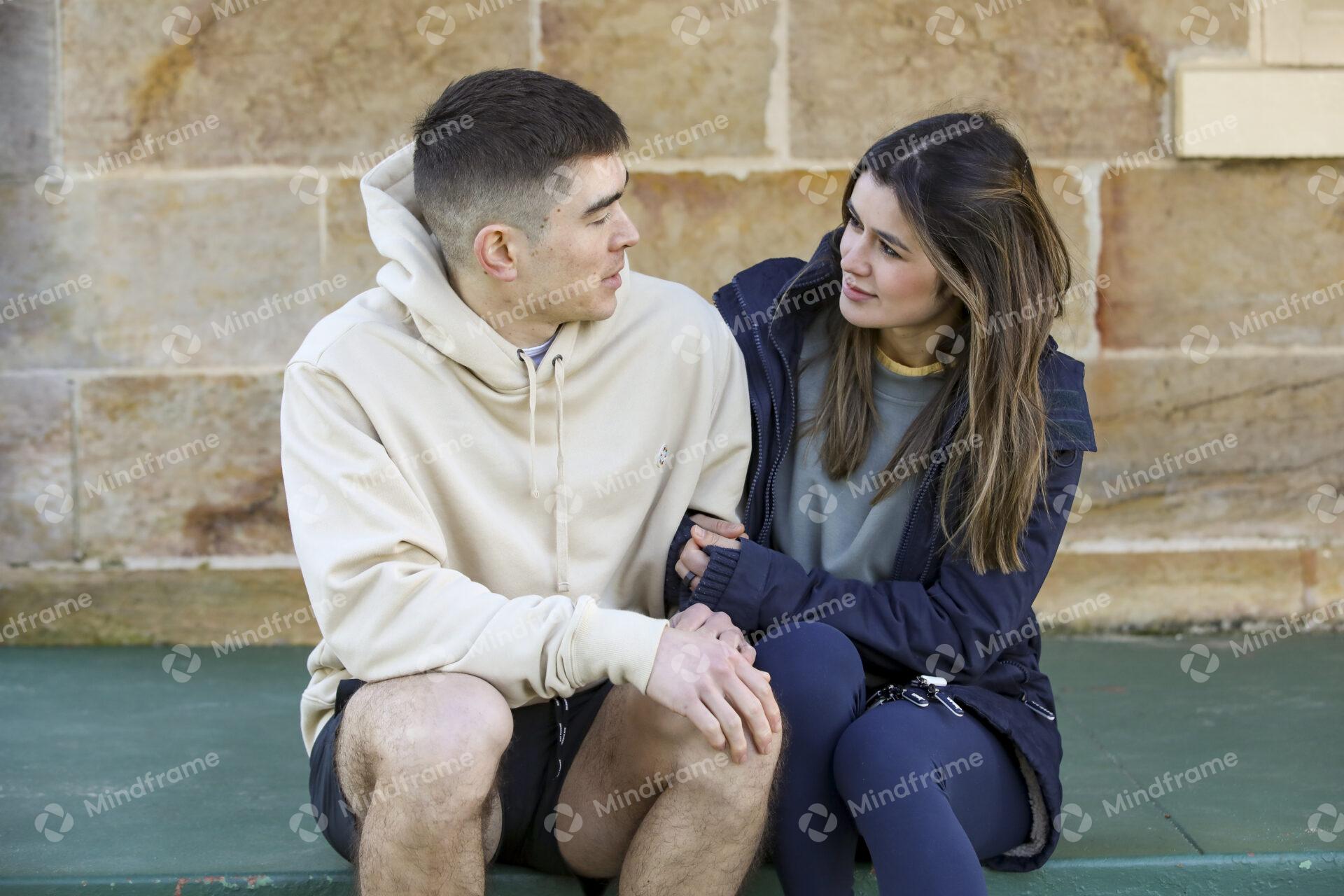 Two people talking and sitting on steps in front building