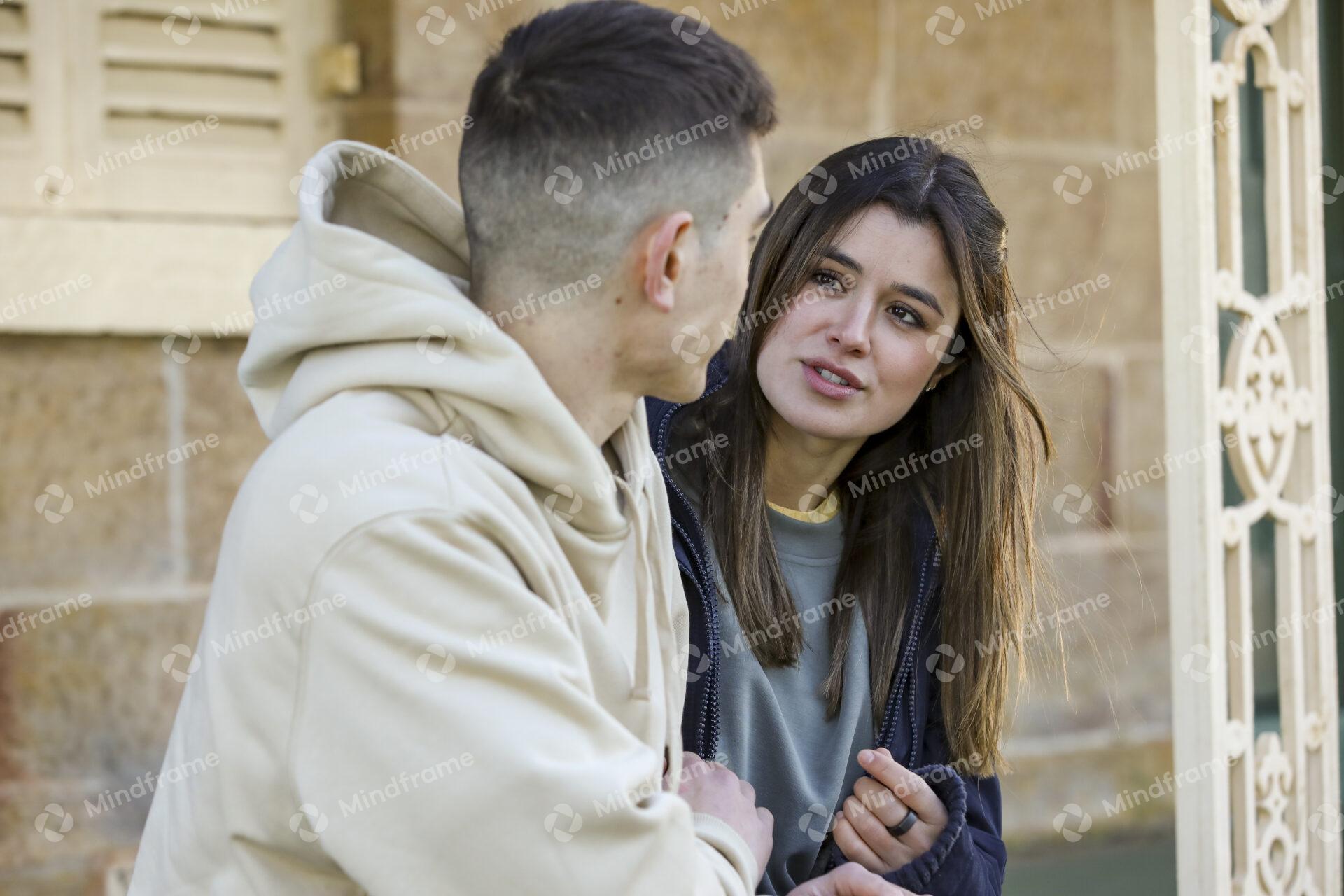 Two people talking and sitting on steps in front of building