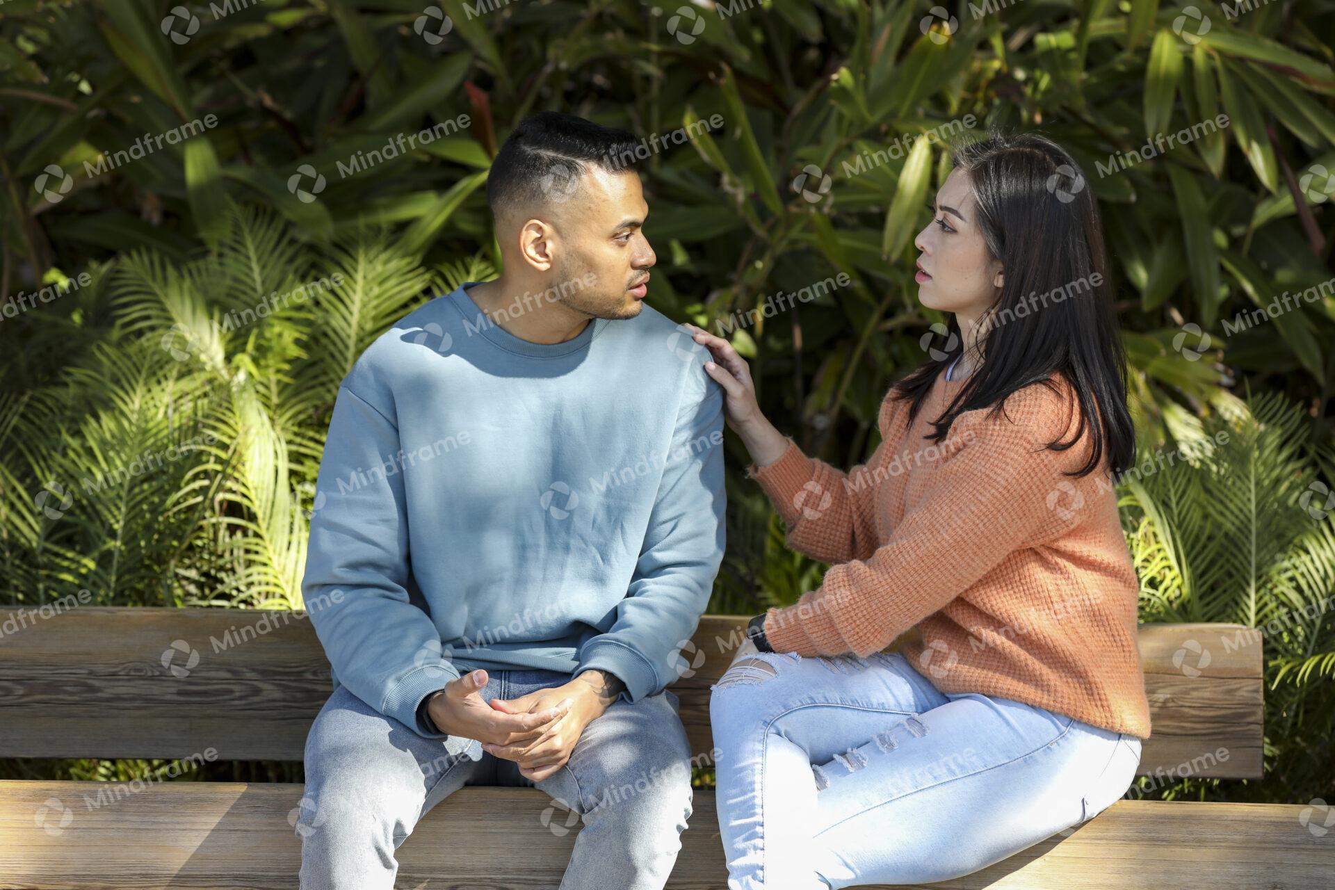 Two people sitting on a park bench and comforting each other
