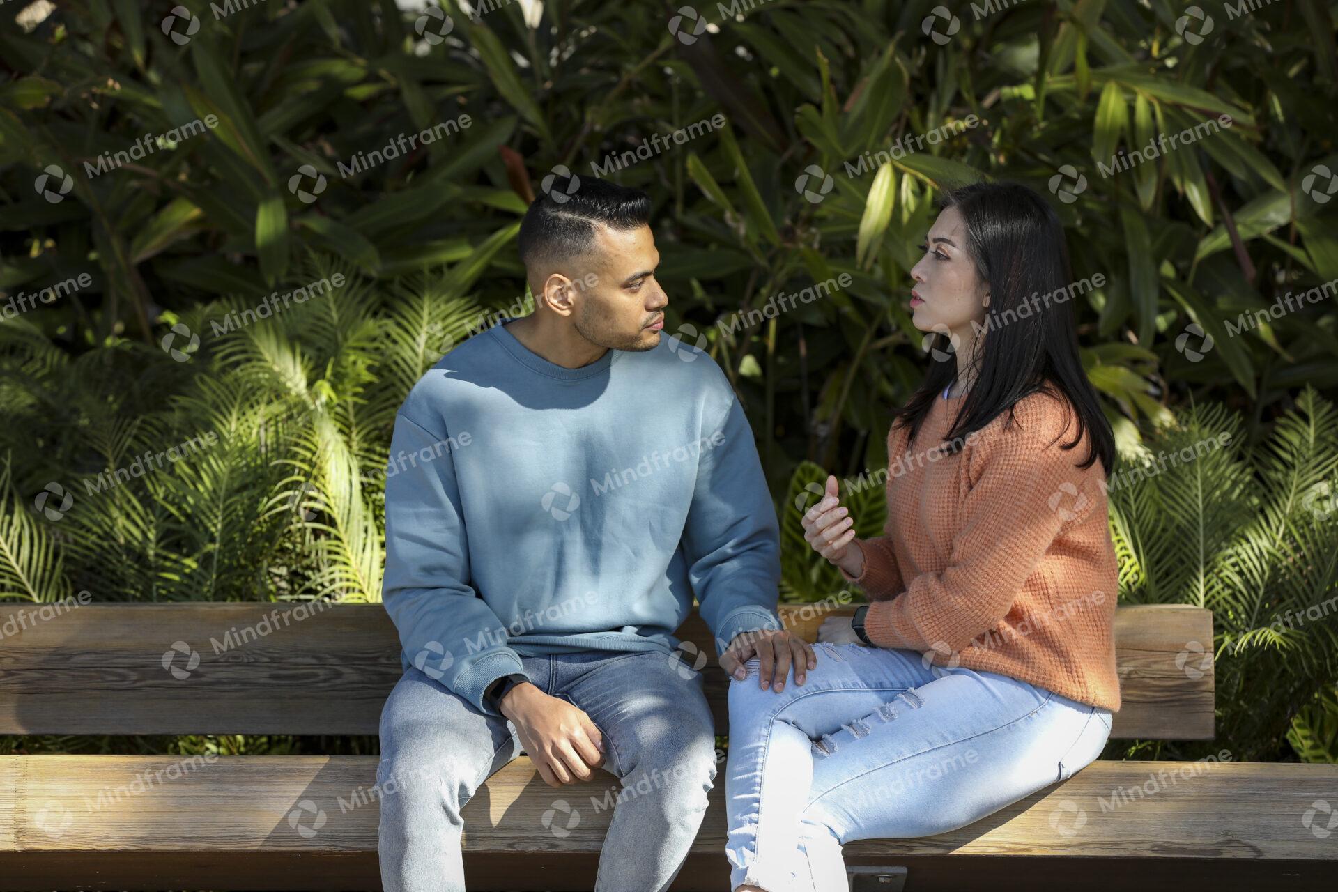 Two people sitting on a park bench and talking to each other