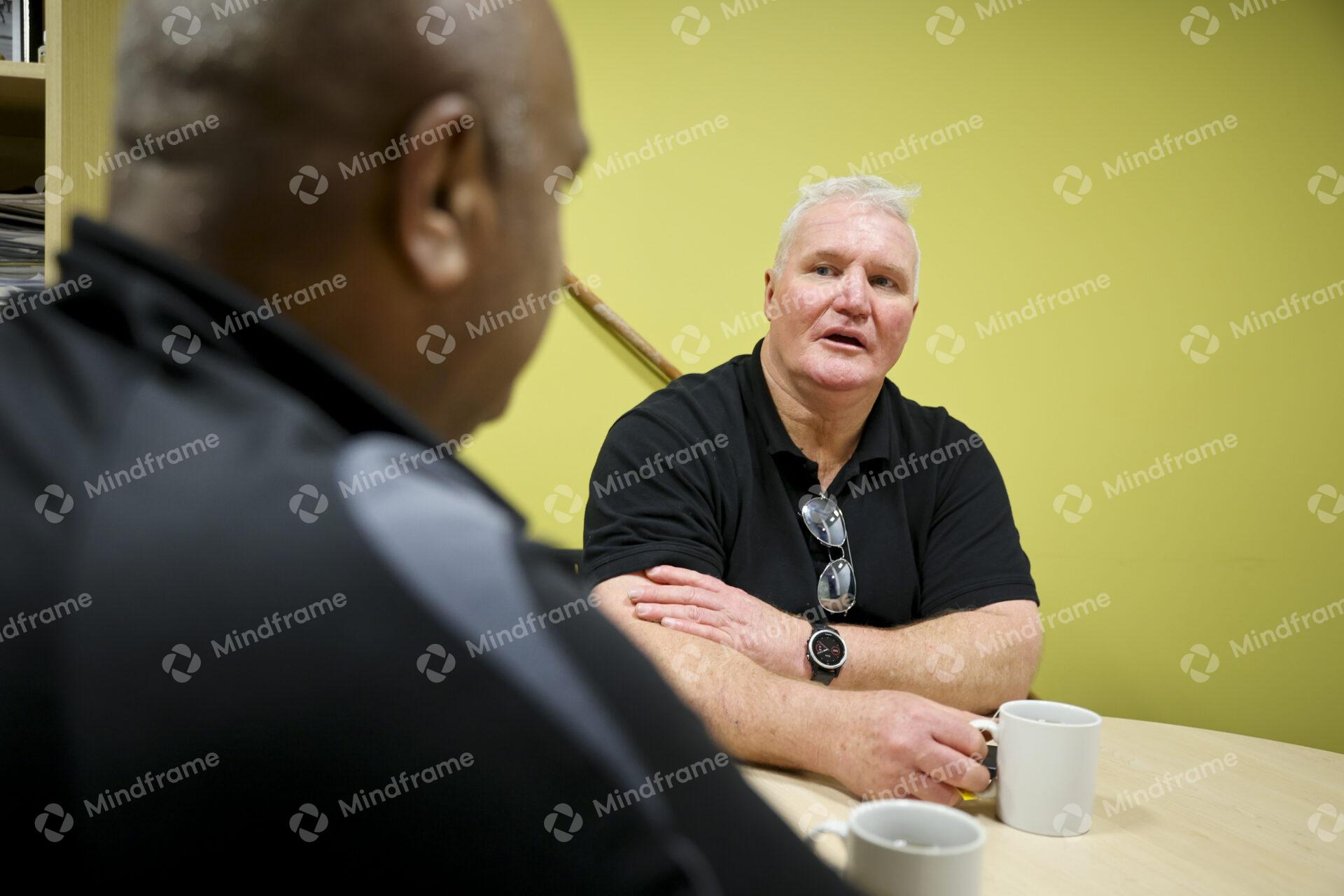 Two men sitting at a table indoors having a conversation