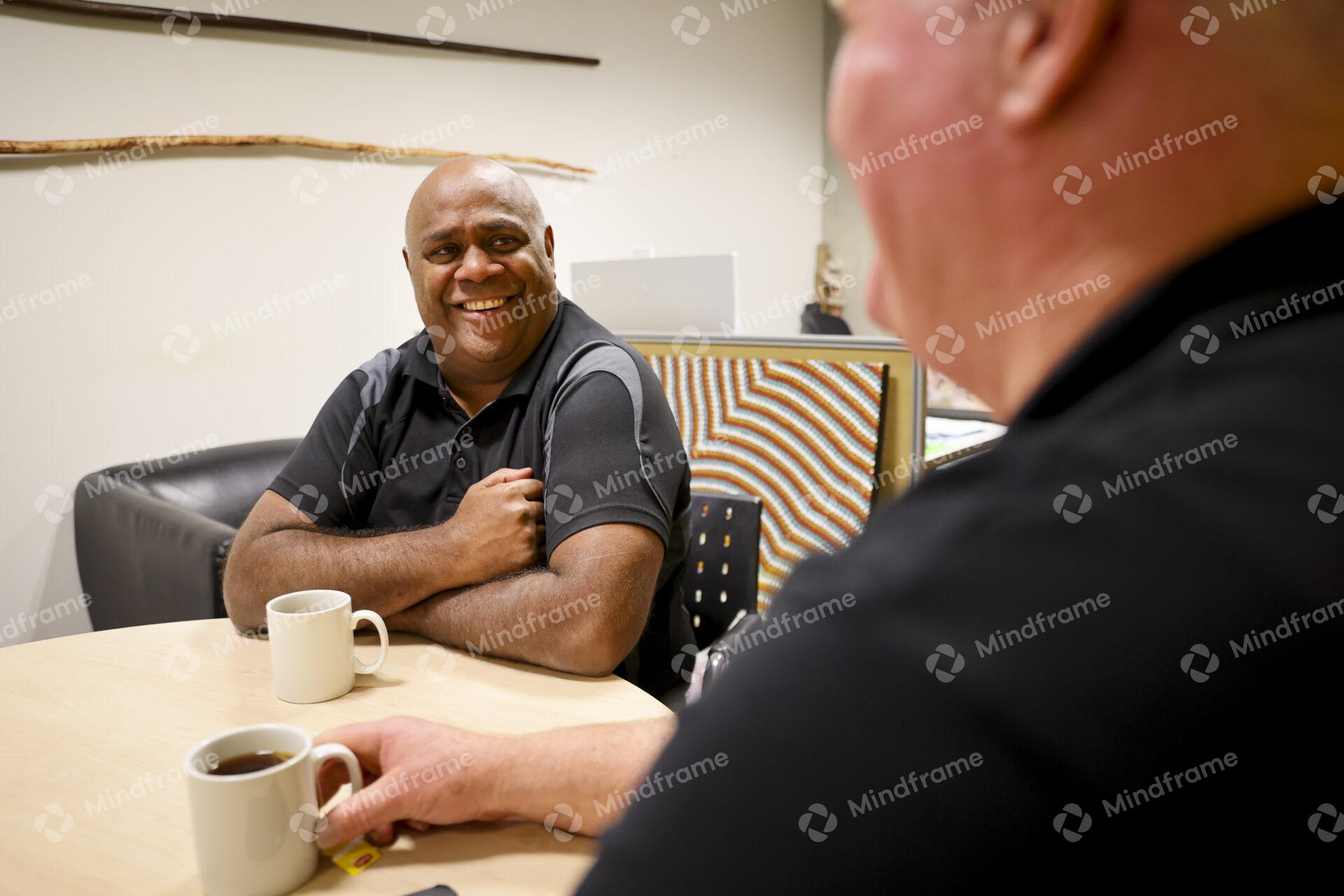 Two men sitting at a table indoors having a conversation