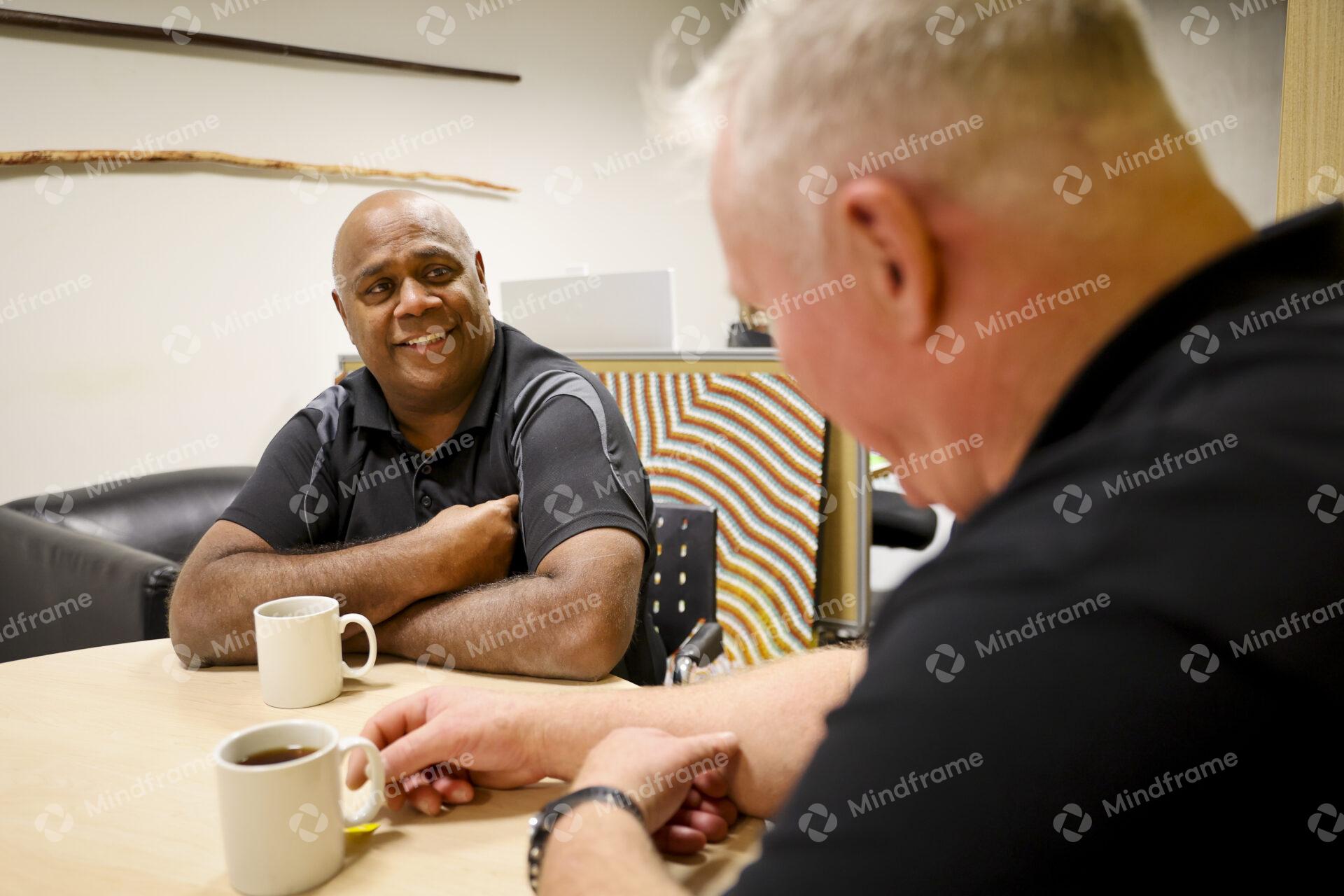 Two men sitting at a table indoors having a conversation