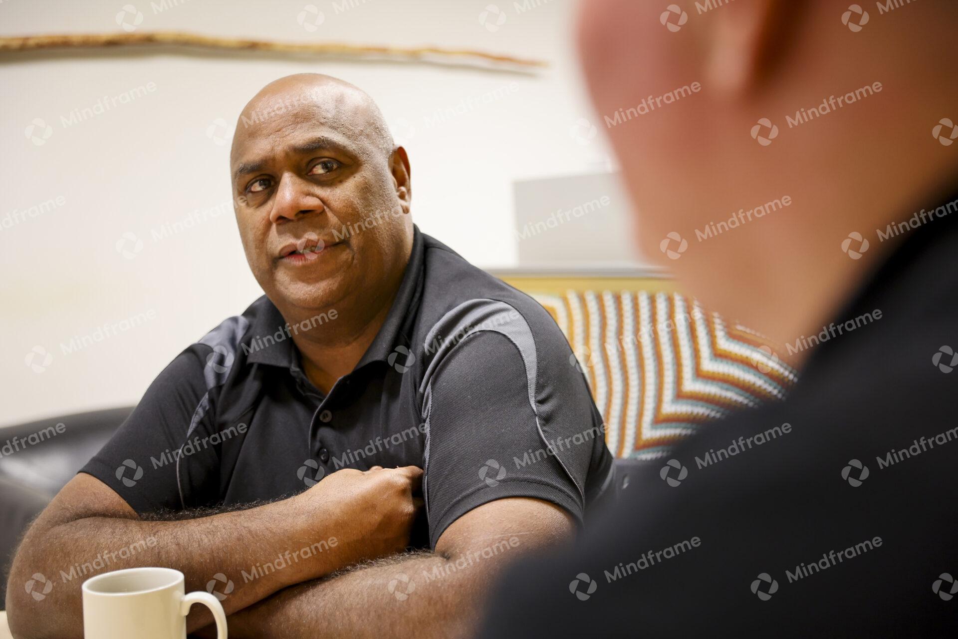 Two men sitting at a table indoors having a conversation