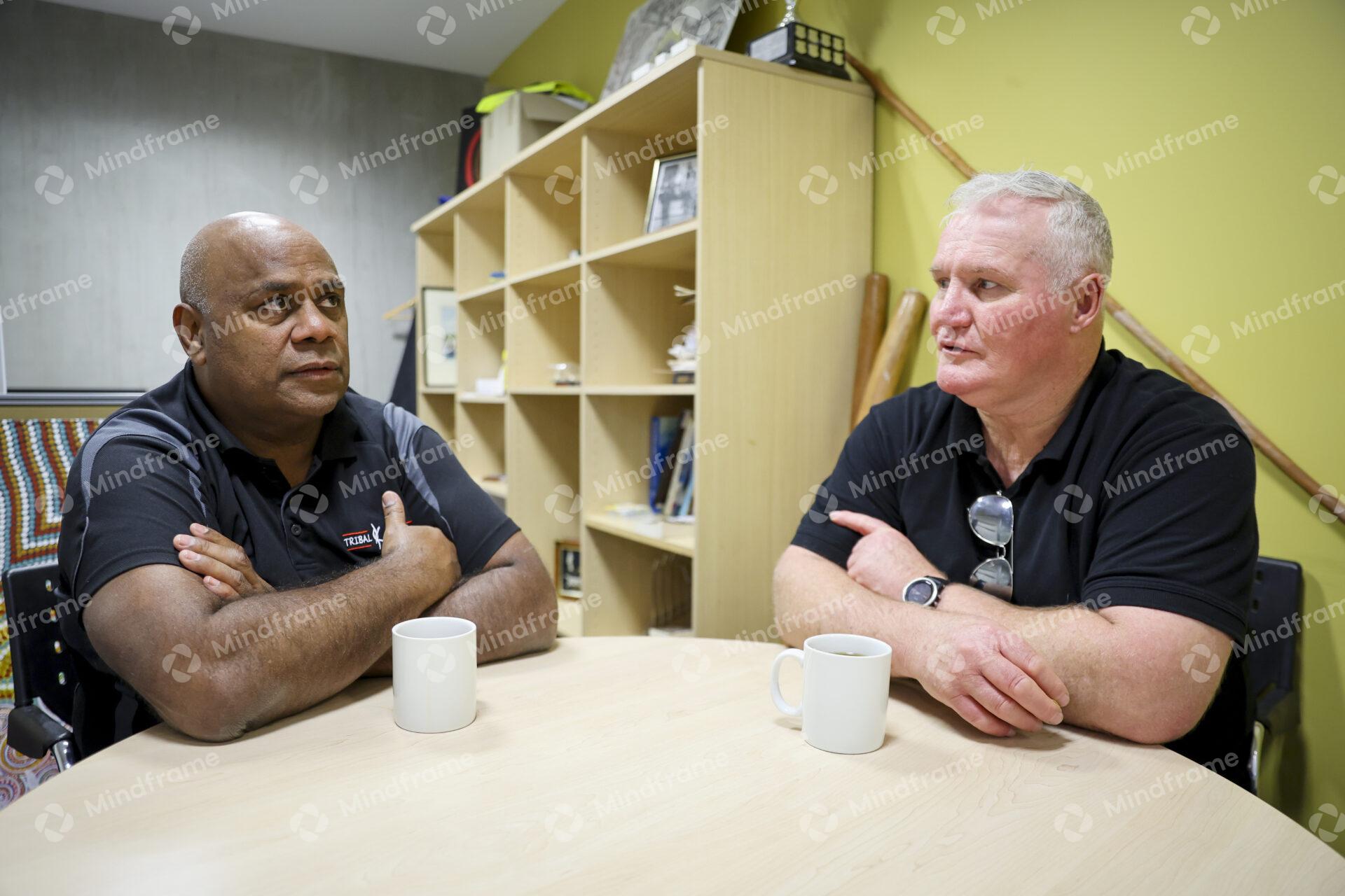 Two men sitting at a table indoors having a conversation