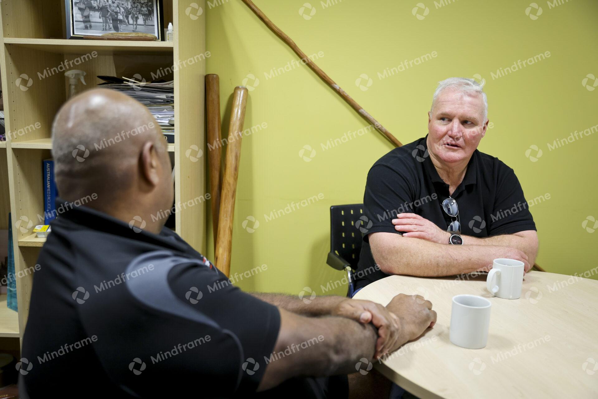 Two men sitting at a table indoors having a conversation