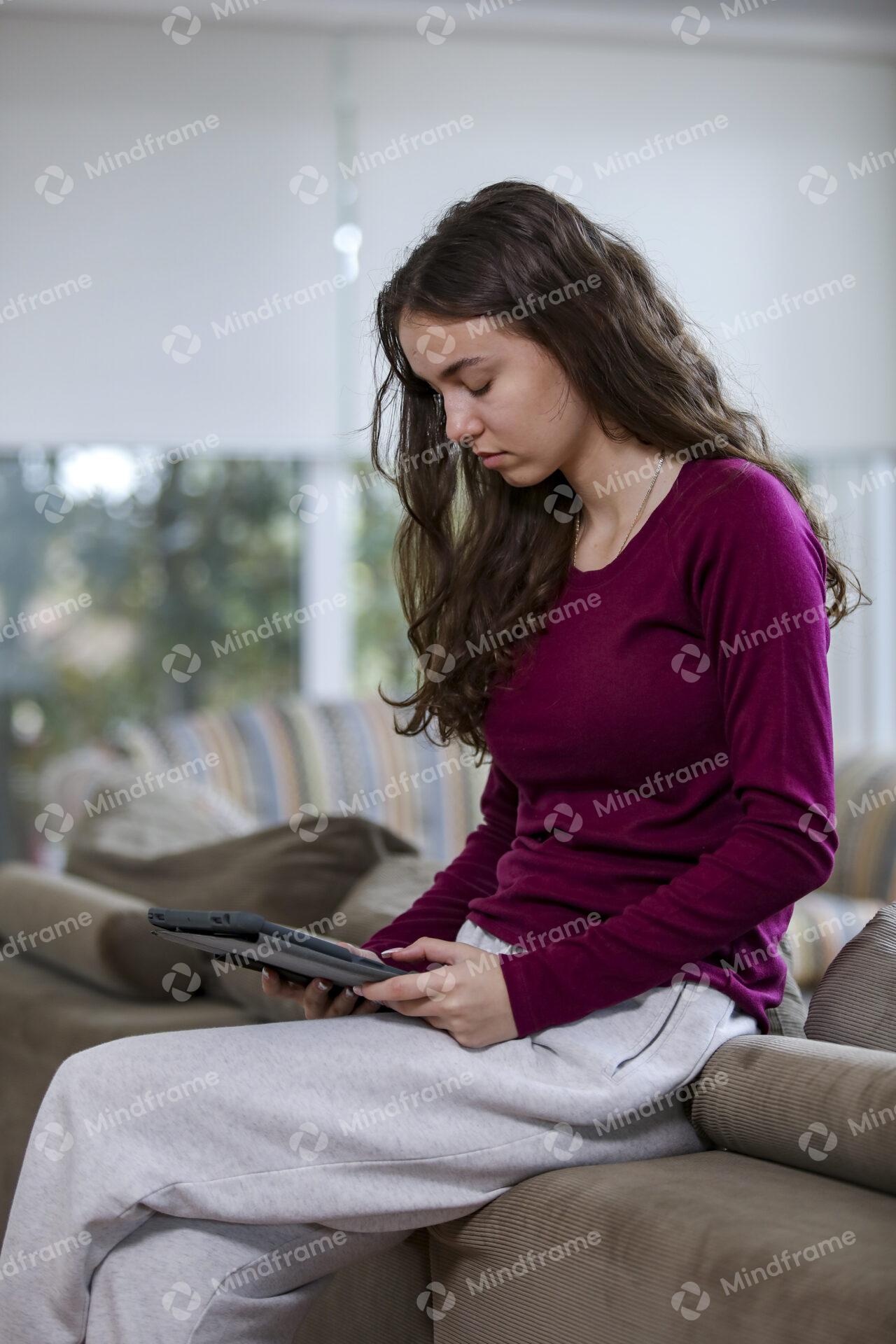 Young person using iPad sitting on back of lounge