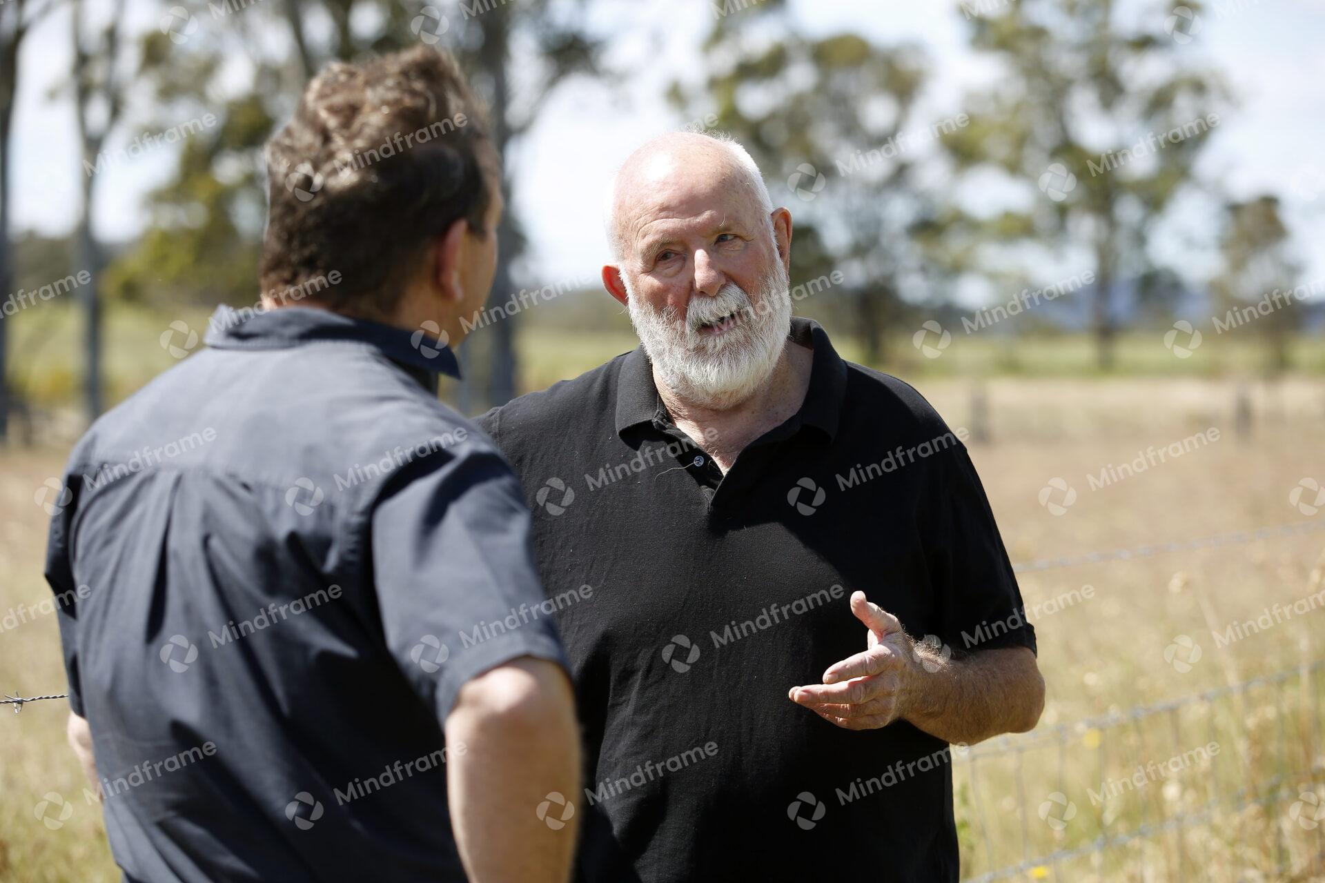 Two people standing by a paddock fence at a farm