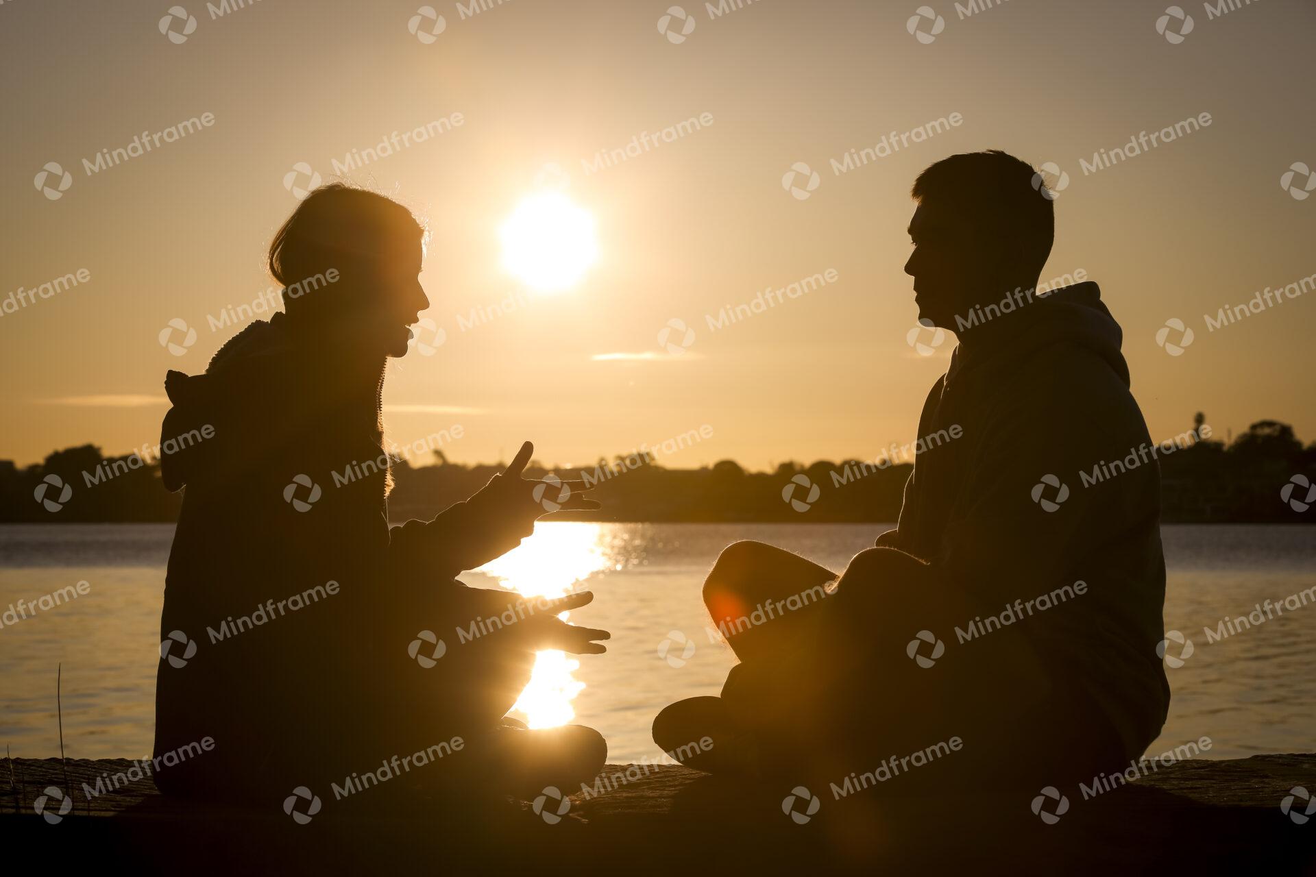 Silhouette of two people at sunset sunrise by the water