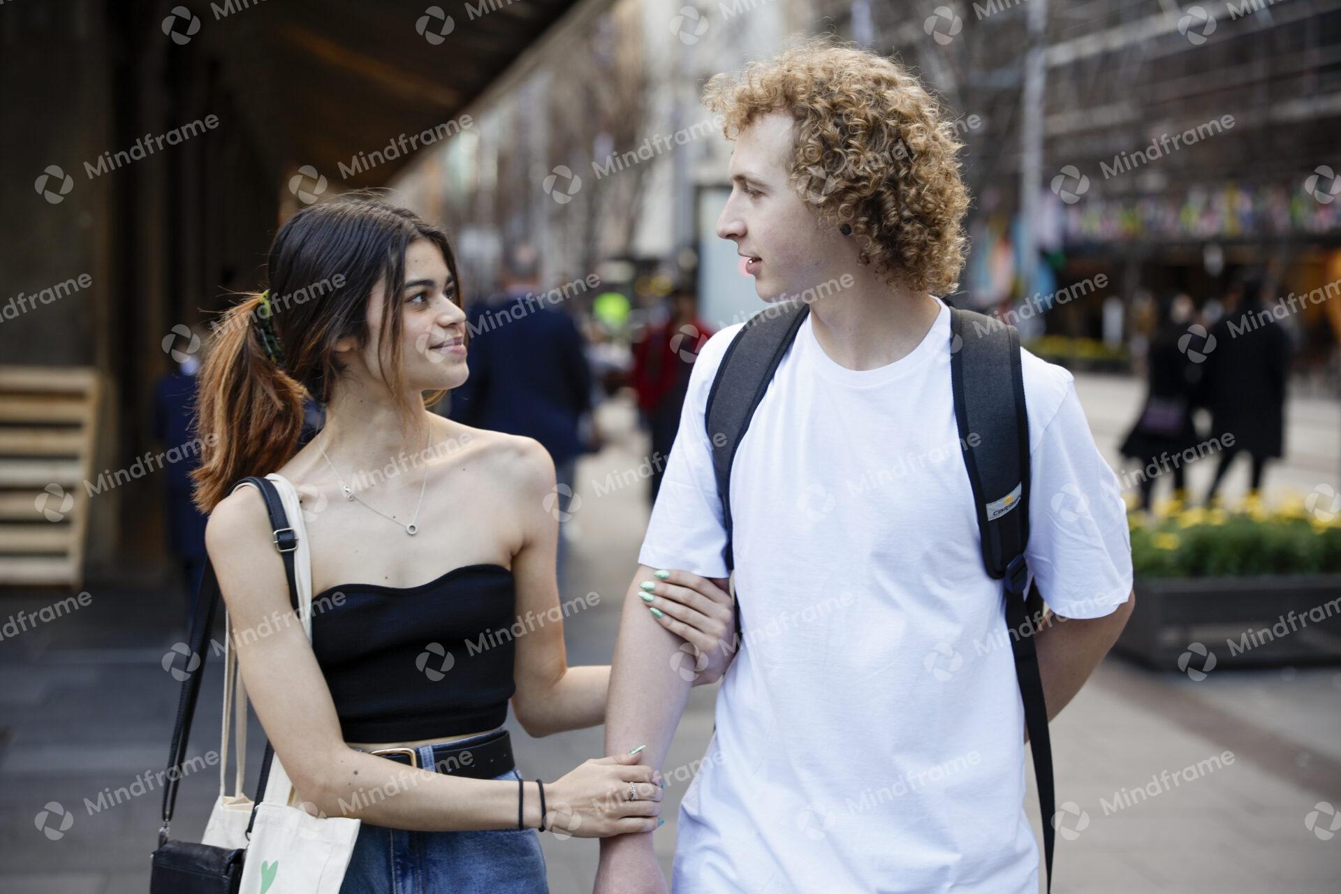 Two people linking arms walking along a city street