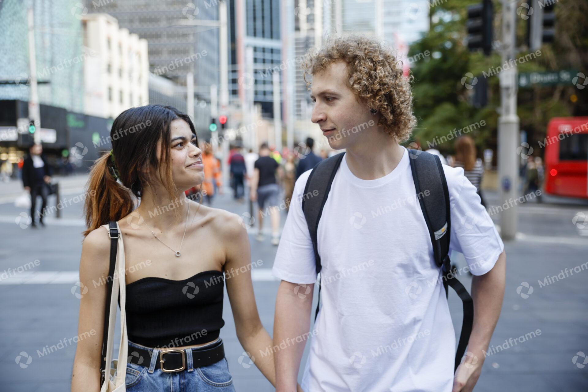 Two people holding hands while walking along a city street
